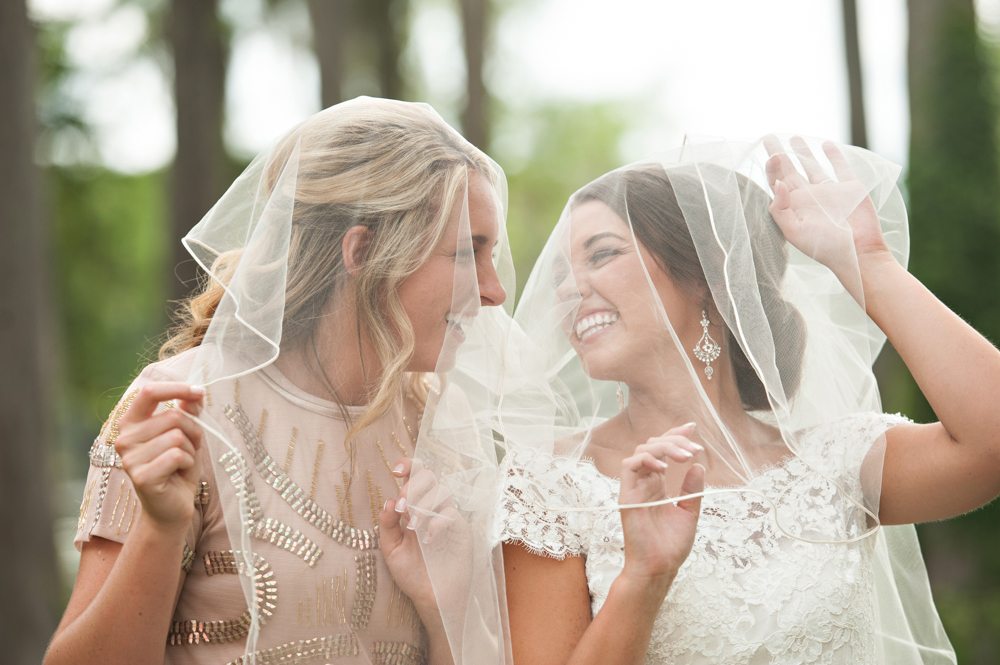 Bride with Bridesmaid playing under the veil