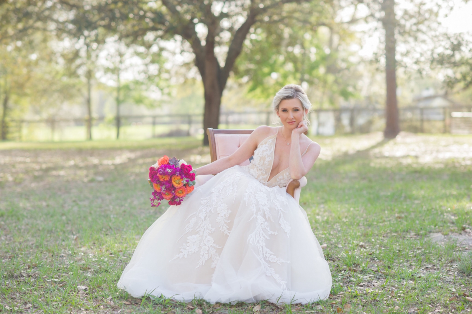 Beautiful Bride sitting in pink chair holding her flowers.
